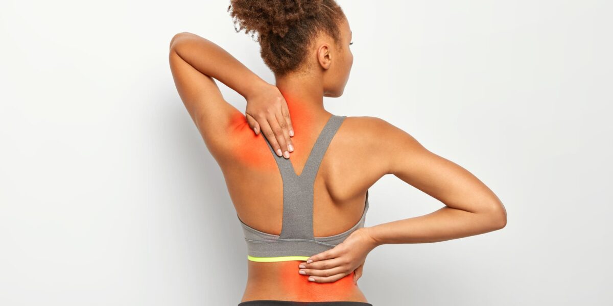 Mulher com as mãos nas costas - problemas na coluna