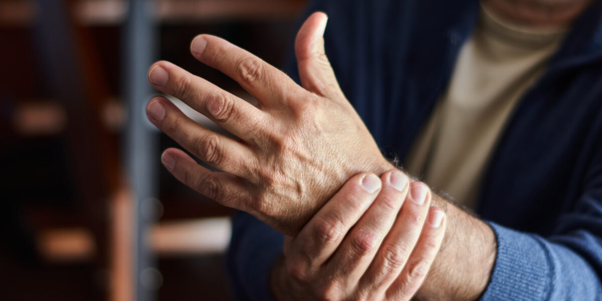 Homem segura o pulso com dor de artrose
